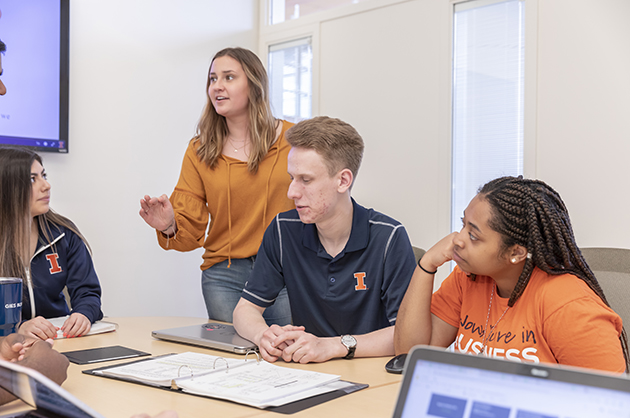 Student Organization Highlight Students working in a group setting with laptops, binders, and an interactive board.
